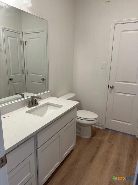 bathroom featuring toilet, wood finished floors, and vanity