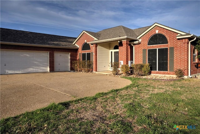 single story home with a garage, concrete driveway, brick siding, and a front yard