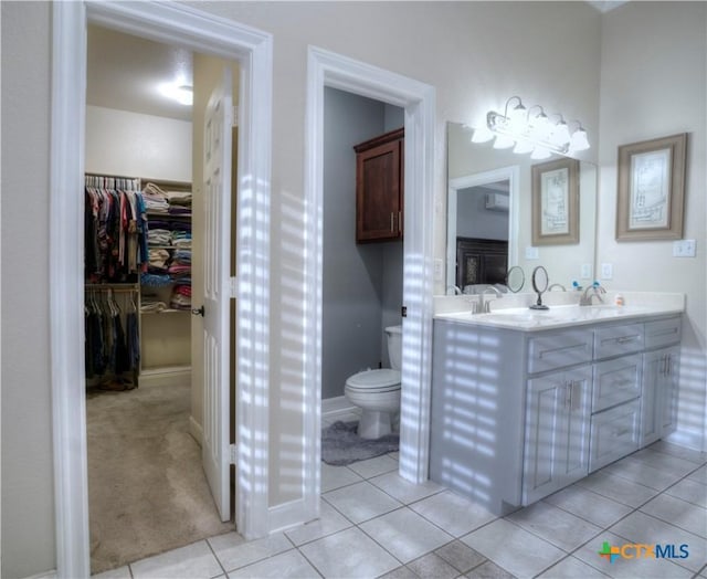 full bathroom with toilet, baseboards, a spacious closet, tile patterned floors, and double vanity