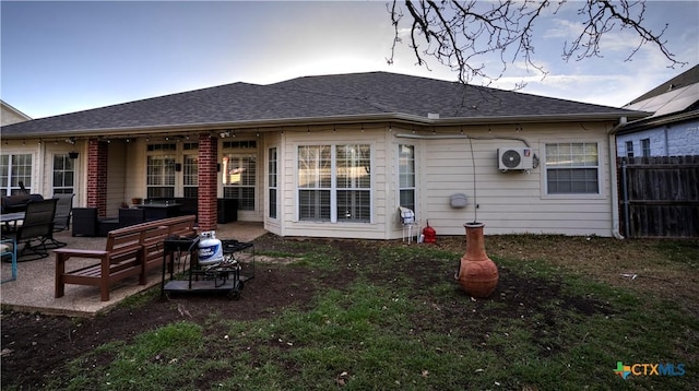 back of property with ac unit, roof with shingles, fence, and a patio