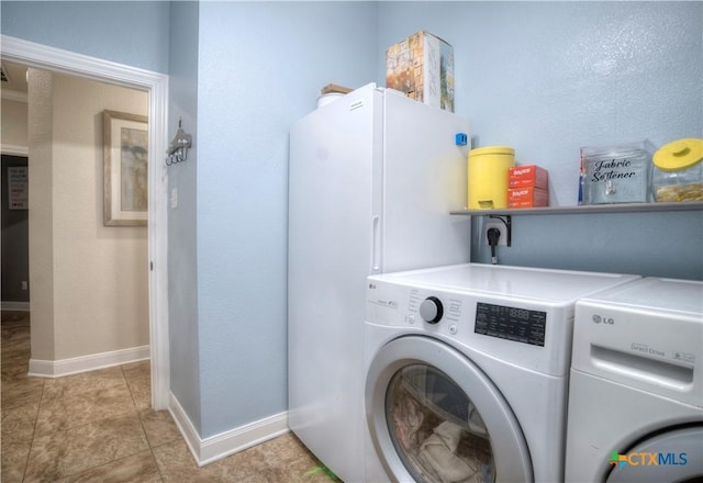 washroom featuring washer and dryer, laundry area, baseboards, and light tile patterned floors