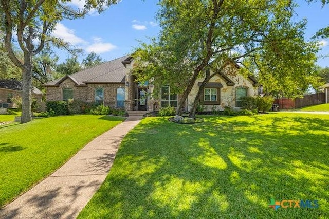 view of front facade with a front lawn, fence, and stone siding