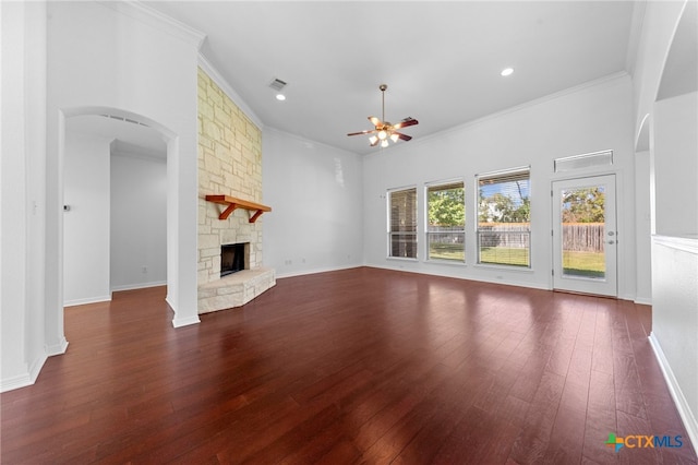 unfurnished living room featuring dark hardwood / wood-style flooring, a stone fireplace, ceiling fan, and crown molding