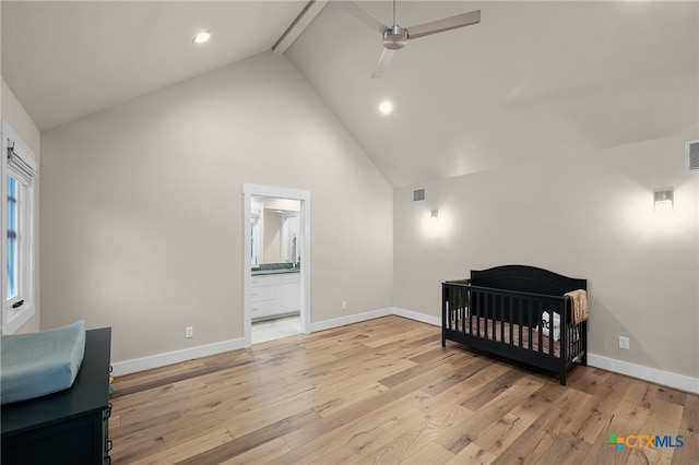 bedroom featuring ensuite bathroom, high vaulted ceiling, ceiling fan, a crib, and light wood-type flooring