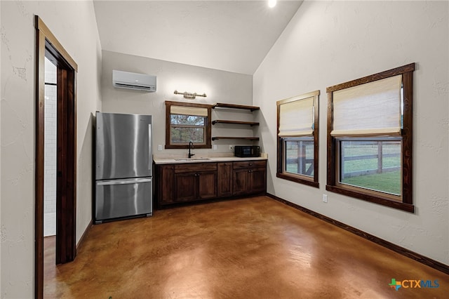 kitchen with lofted ceiling, a wall mounted AC, sink, dark brown cabinets, and stainless steel fridge