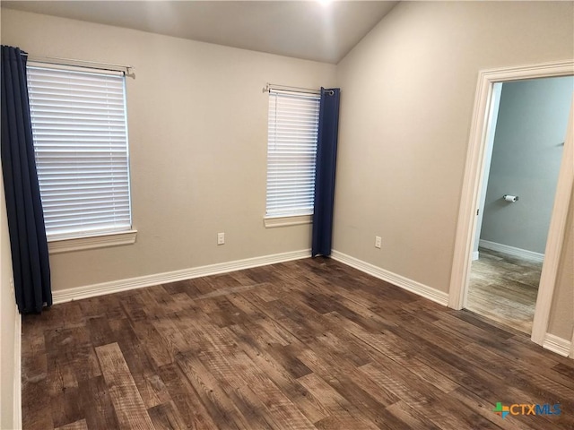 spare room featuring lofted ceiling and dark hardwood / wood-style floors