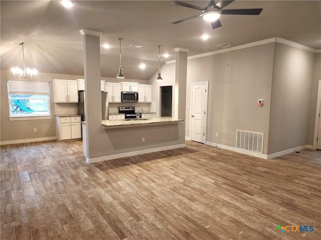 kitchen featuring appliances with stainless steel finishes, white cabinets, and decorative light fixtures