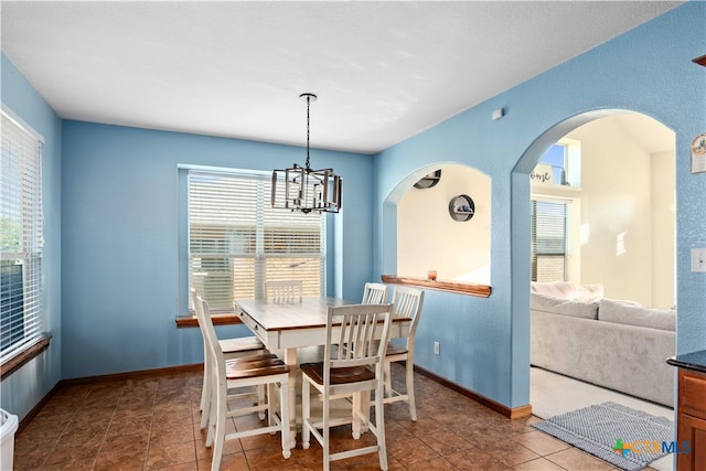 dining room with dark tile patterned floors, a notable chandelier, and plenty of natural light