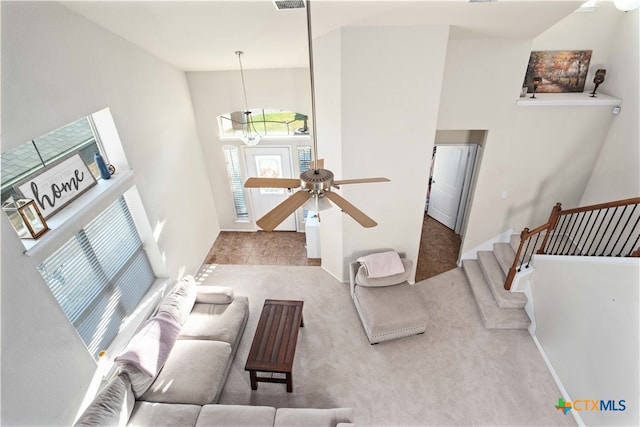 living room with a towering ceiling and ceiling fan with notable chandelier