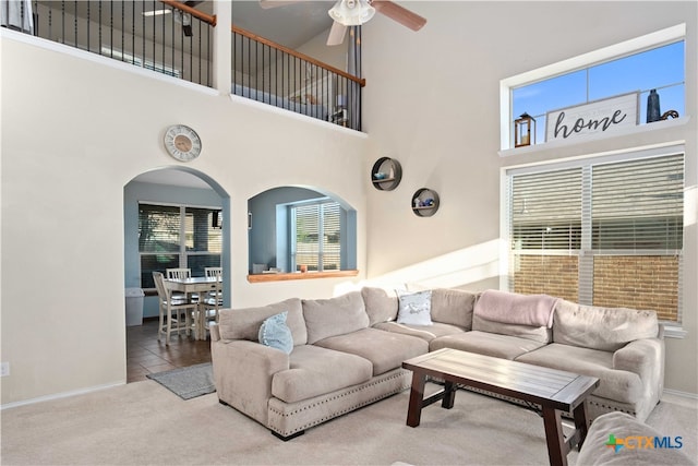 living room featuring a high ceiling, ceiling fan, tile patterned floors, and a healthy amount of sunlight