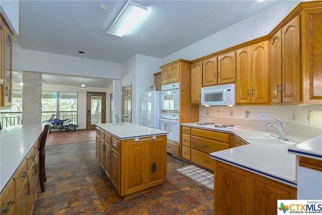 kitchen featuring white appliances, sink, ornate columns, and a center island