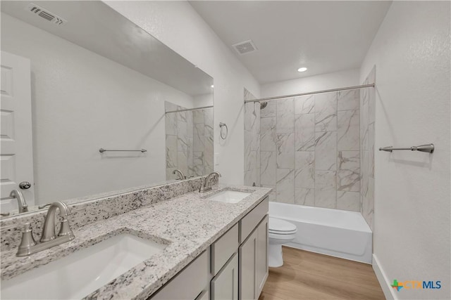 full bathroom featuring tiled shower / bath, vanity, wood-type flooring, and toilet