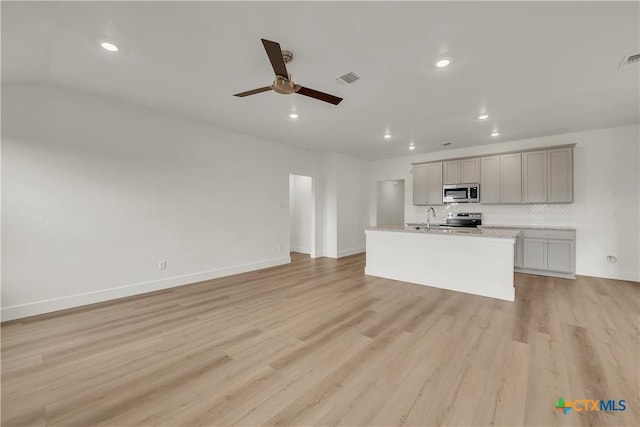 unfurnished living room with ceiling fan, light hardwood / wood-style flooring, and sink