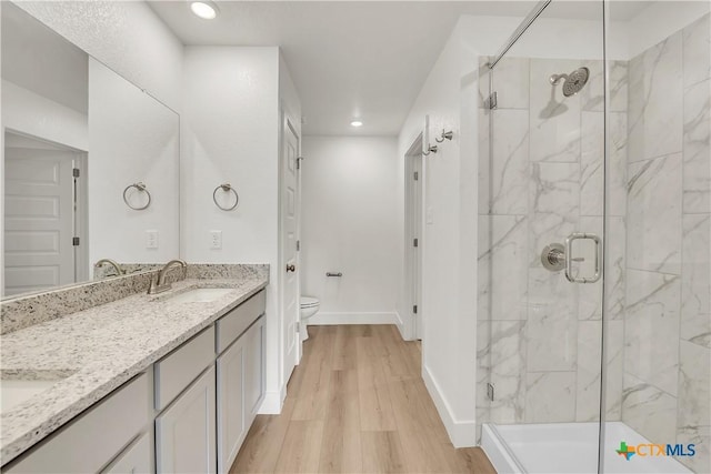 bathroom with vanity, hardwood / wood-style flooring, toilet, and a shower with door