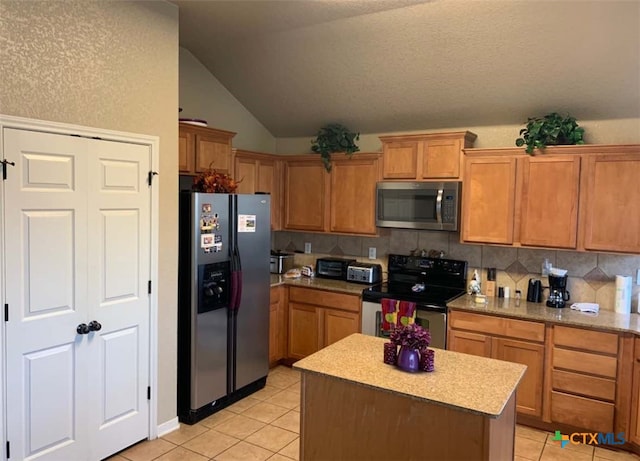 kitchen with a kitchen island, lofted ceiling, light tile patterned flooring, and stainless steel appliances