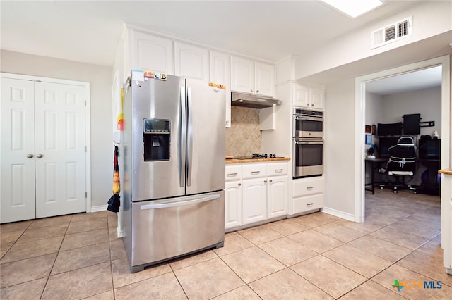 kitchen with appliances with stainless steel finishes, light tile patterned floors, and white cabinetry