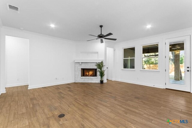 4121 Turning Leaf Dr, Nolanville, TX 76559 - unfurnished living room with ornamental molding, a ceiling fan, wood finished floors, a stone fireplace, and baseboards