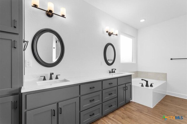 4121 Turning Leaf Dr, Nolanville, TX 76559 - bathroom featuring double vanity, wood finished floors, a garden tub, baseboards, and recessed lighting
