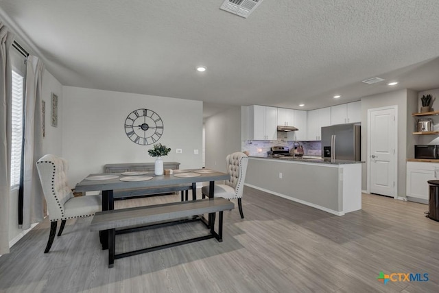 dining room featuring recessed lighting, light wood finished floors, visible vents, and a textured ceiling