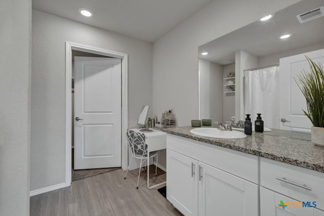 bathroom with vanity, visible vents, recessed lighting, wood finished floors, and baseboards
