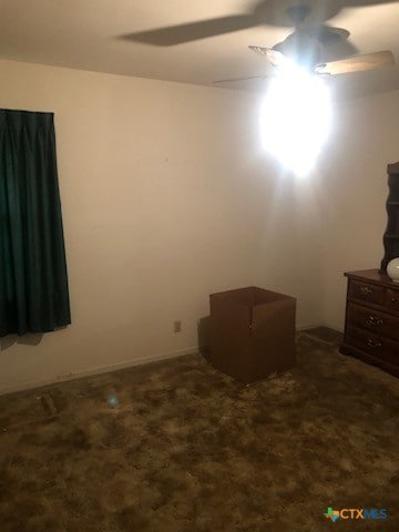 unfurnished bedroom featuring dark carpet and ceiling fan