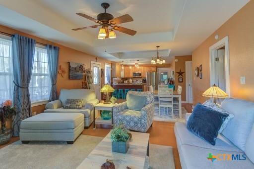 162 Canyon Crk, Canyon Lake, TX 78133 - living area featuring plenty of natural light, ceiling fan with notable chandelier, and a raised ceiling