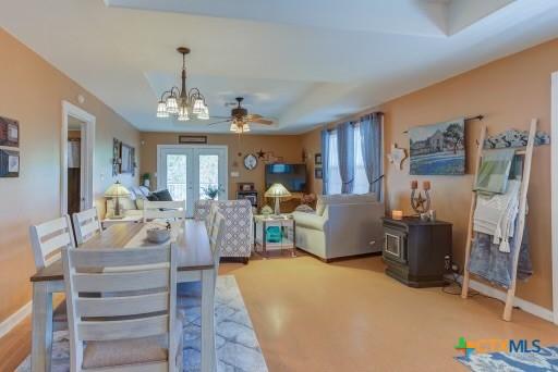 162 Canyon Crk, Canyon Lake, TX 78133 - dining room with french doors, ceiling fan with notable chandelier, baseboards, and a wood stove