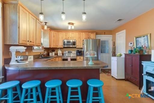 162 Canyon Crk, Canyon Lake, TX 78133 - kitchen featuring visible vents, a peninsula, a kitchen bar, stainless steel appliances, and a sink