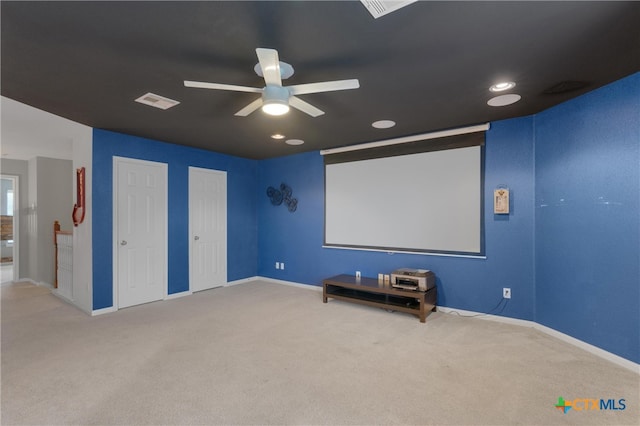 home theater room with ceiling fan and light colored carpet