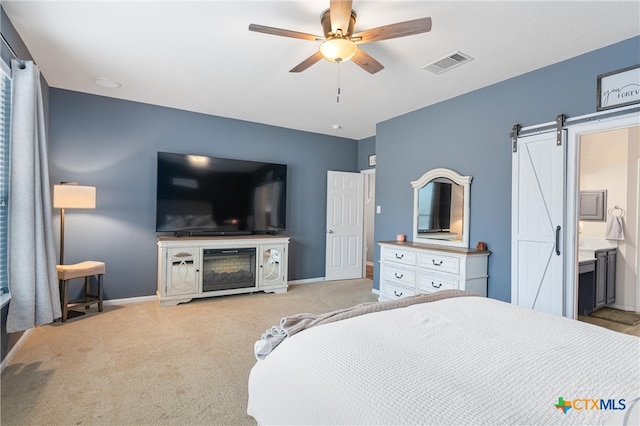 carpeted bedroom with a barn door, ceiling fan, and connected bathroom