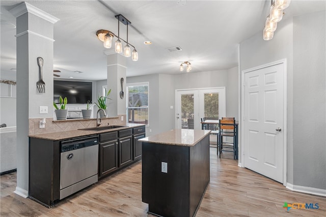 kitchen with light wood-type flooring, stainless steel dishwasher, a center island, and sink