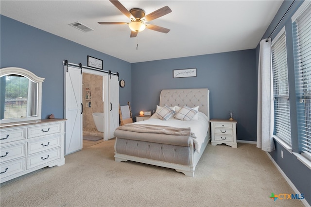 carpeted bedroom featuring ensuite bath, a barn door, and ceiling fan