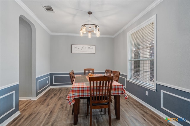 dining space with crown molding, an inviting chandelier, and dark hardwood / wood-style flooring