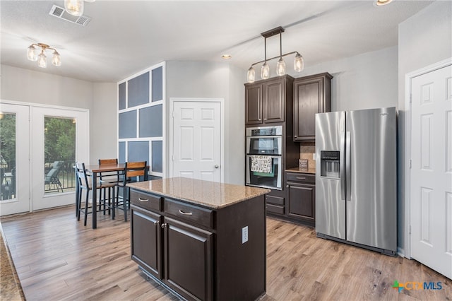 kitchen featuring stainless steel appliances, a kitchen island, light wood-type flooring, dark brown cabinetry, and pendant lighting