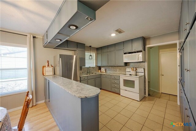 207 River St, Hallettsville, TX 77964 - kitchen featuring white appliances, gray cabinets, a sink, and a peninsula