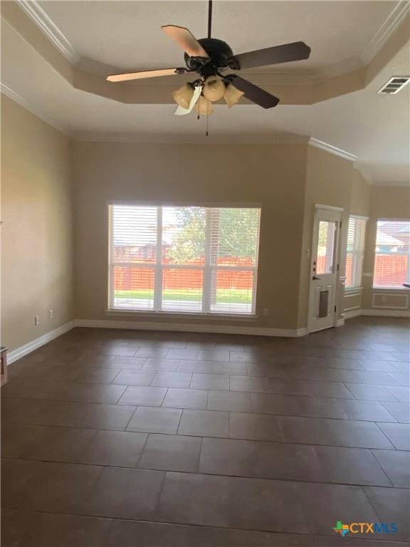 tiled empty room featuring a raised ceiling, ceiling fan, and ornamental molding