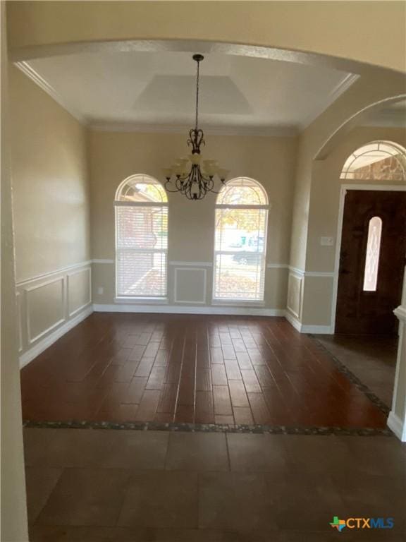 2504 Boxwood Dr, Harker Heights, TX 76548 - unfurnished dining area featuring a chandelier, healthy amount of natural light, arched walkways, a decorative wall, and crown molding