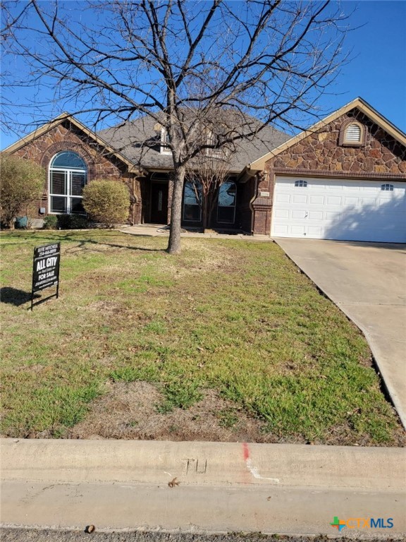 ranch-style house featuring a garage, concrete driveway, brick siding, and a front lawn