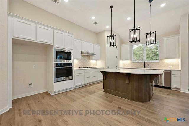 kitchen with appliances with stainless steel finishes, an inviting chandelier, decorative backsplash, and white cabinetry