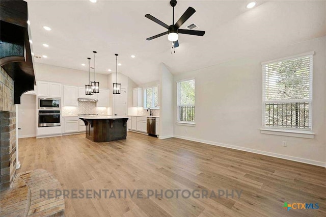 kitchen with tasteful backsplash, appliances with stainless steel finishes, a kitchen island, ceiling fan, and open floor plan