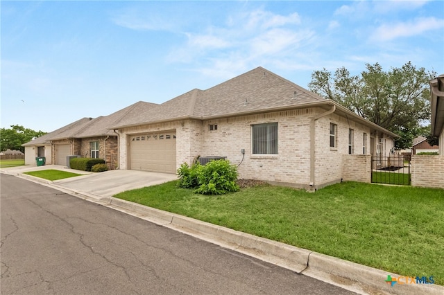 view of front of home featuring fence, an attached garage, a shingled roof, brick siding, and a front yard