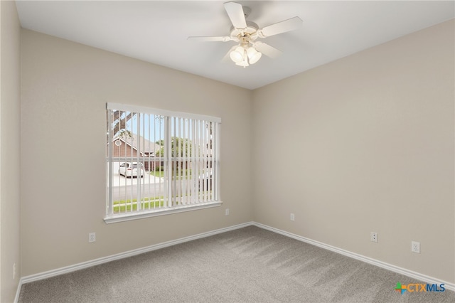 carpeted spare room featuring a ceiling fan and baseboards
