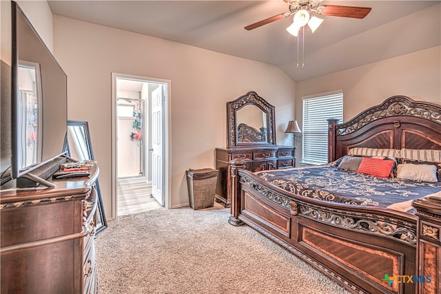 carpeted bedroom with ceiling fan, connected bathroom, and vaulted ceiling