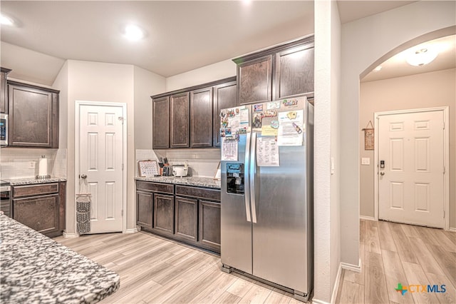 kitchen with stainless steel appliances, dark brown cabinets, and light hardwood / wood-style floors