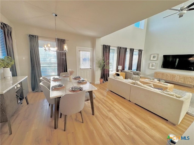 dining space featuring ceiling fan with notable chandelier, plenty of natural light, and light wood-style flooring