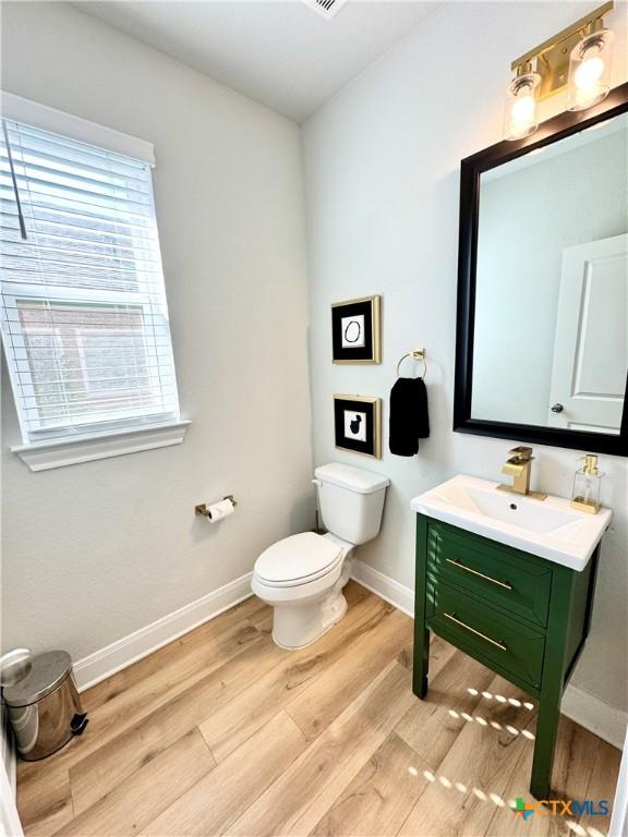 bathroom featuring vanity, wood finished floors, toilet, and baseboards