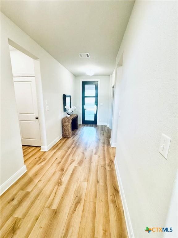 corridor featuring light wood-style floors, visible vents, and baseboards