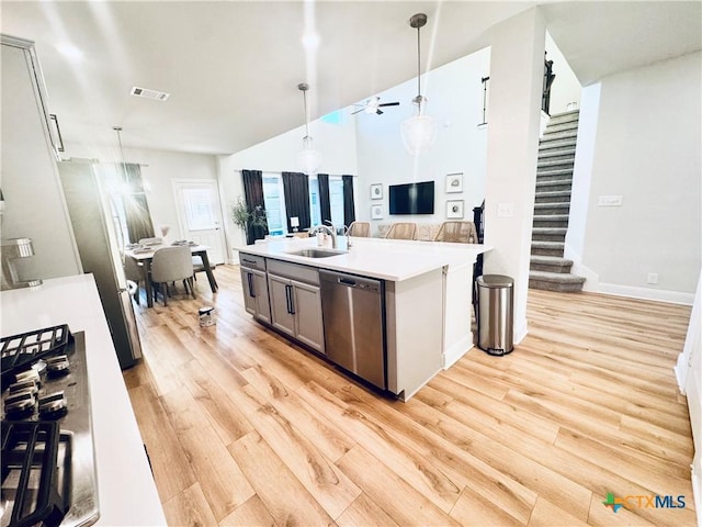 kitchen featuring light wood finished floors, visible vents, appliances with stainless steel finishes, hanging light fixtures, and a sink