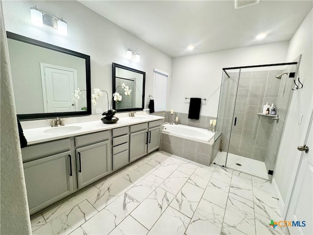 full bathroom with marble finish floor, a garden tub, a sink, and a shower stall