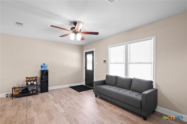 living room featuring baseboards, visible vents, and ceiling fan